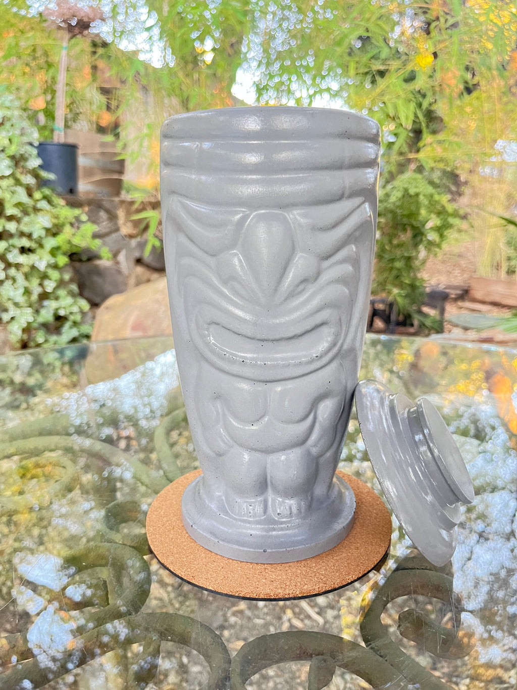 Rencarie Tiki tabletop fire pit in light grey with lid removed, on a glass patio table