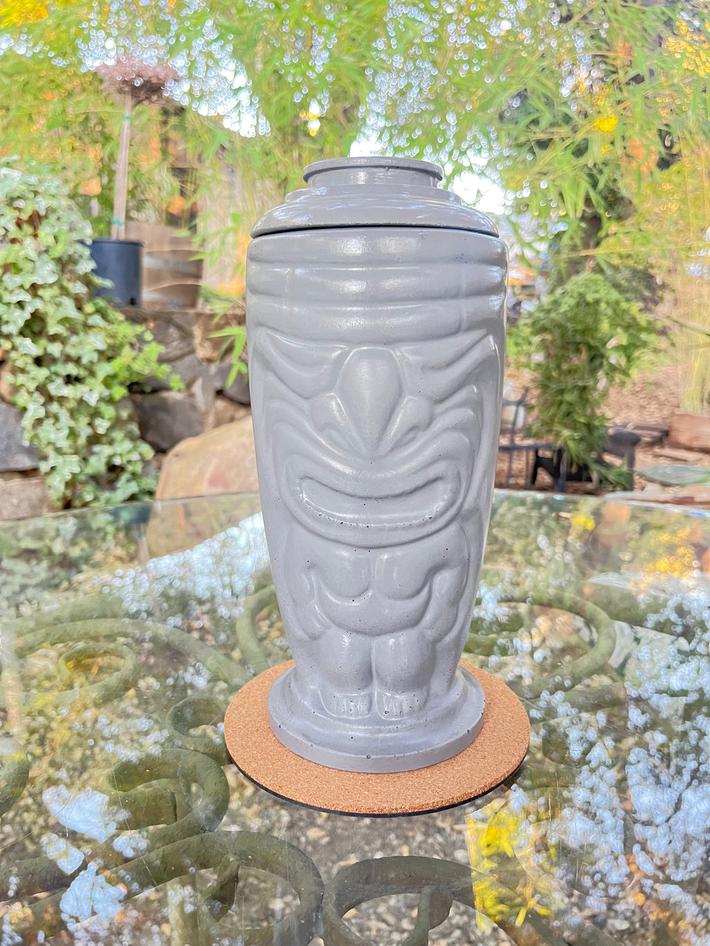 Rencarie Tiki tabletop fire pit in light grey with lid on, on a glass patio table