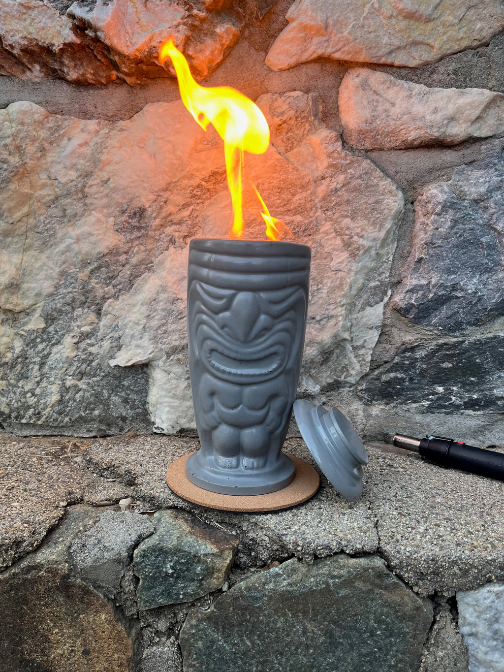 Rencarie Tiki tabletop fire pit lit against a stone wall